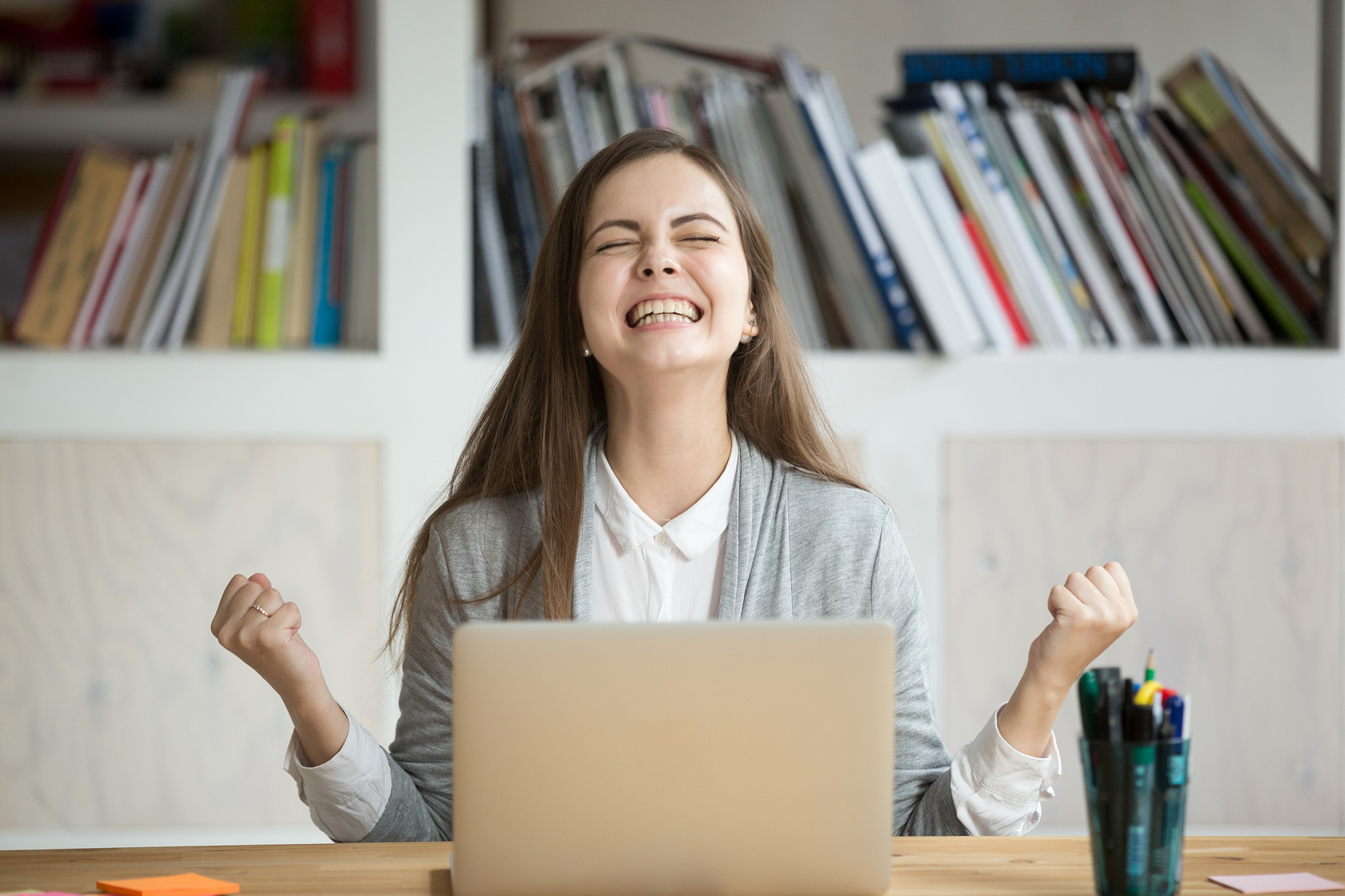 Happy woman at dental office front desk with laptop