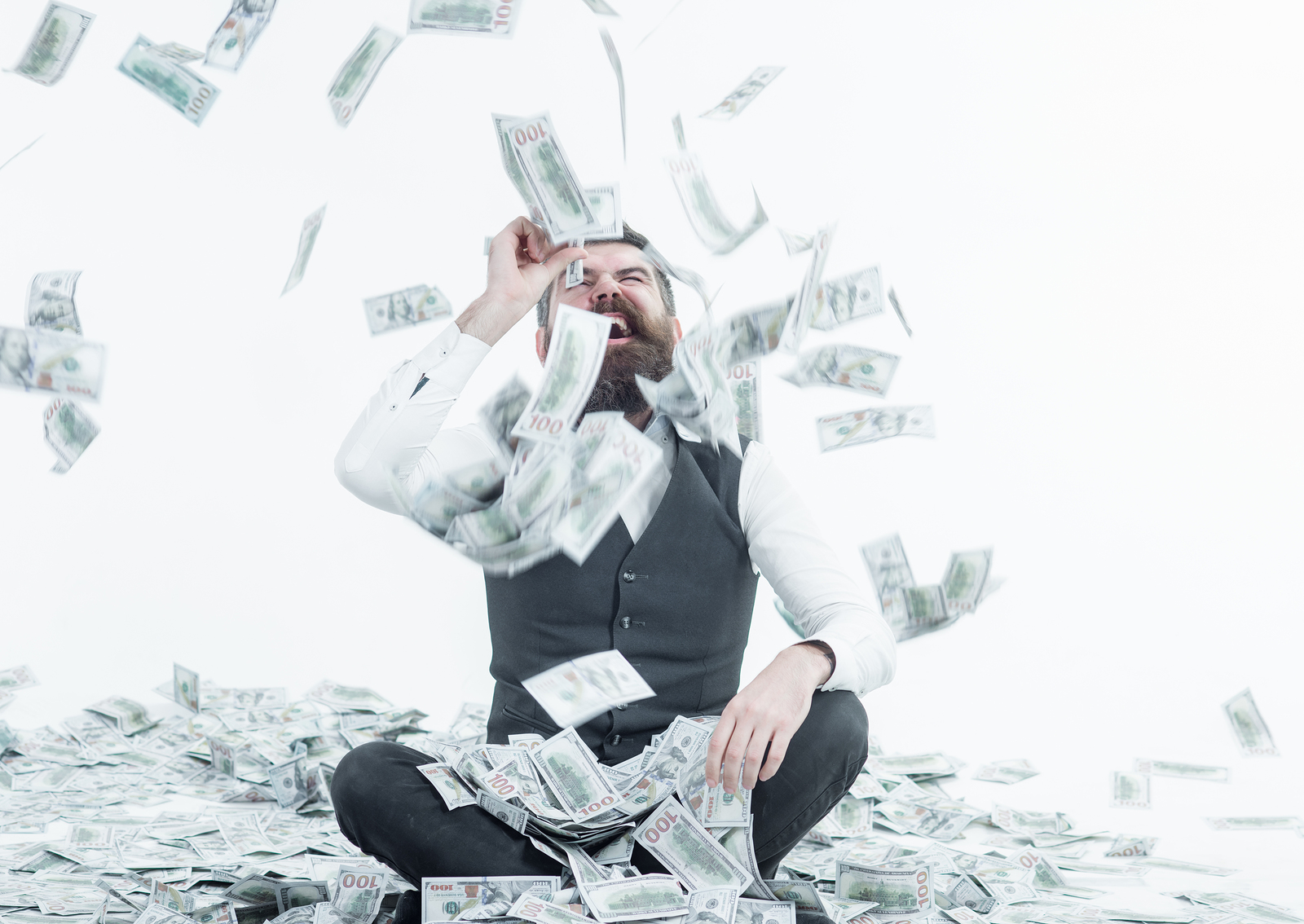 Man in business attire sitting down and laughing in greed about dental web agencies among a shower of hundred dollar bills