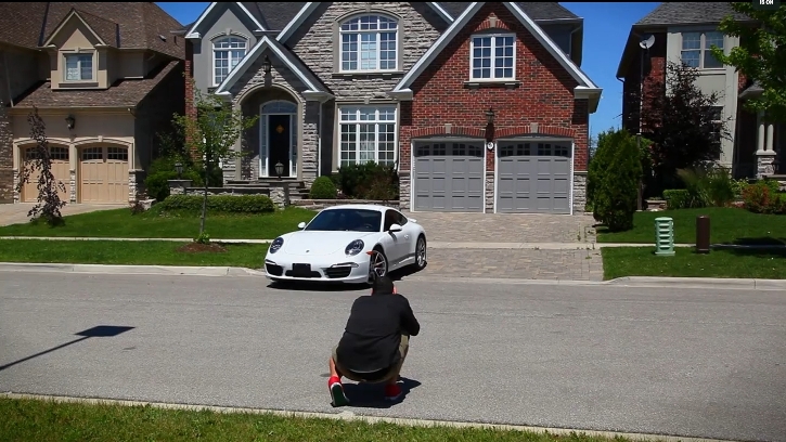photographer taking a picture of a new, white Porsche positioned in the driveway of an upscale home